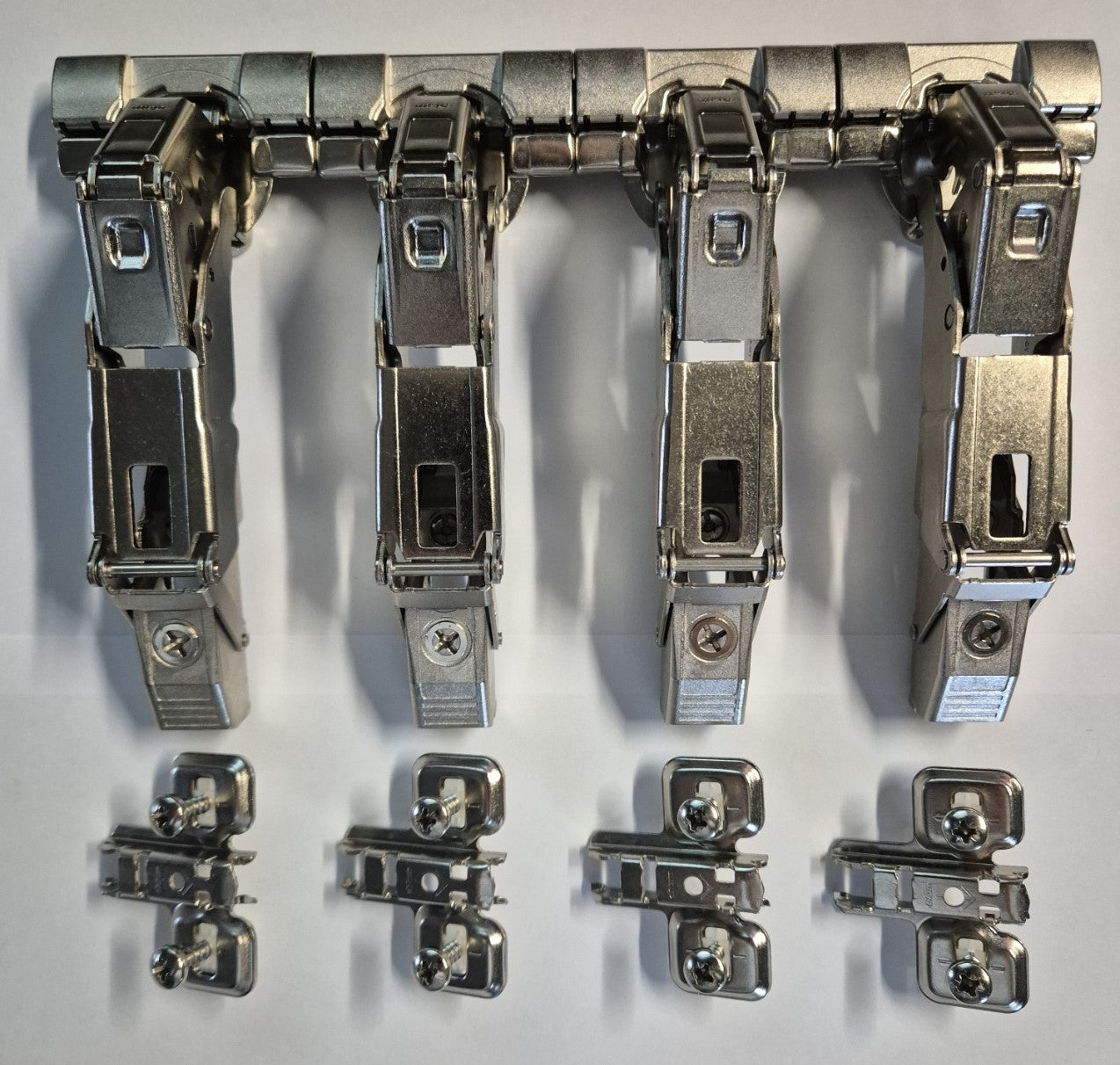 Vier Blum 155-Grad-Eckscharniere mit passenden Montageplatten für Eckschränke.