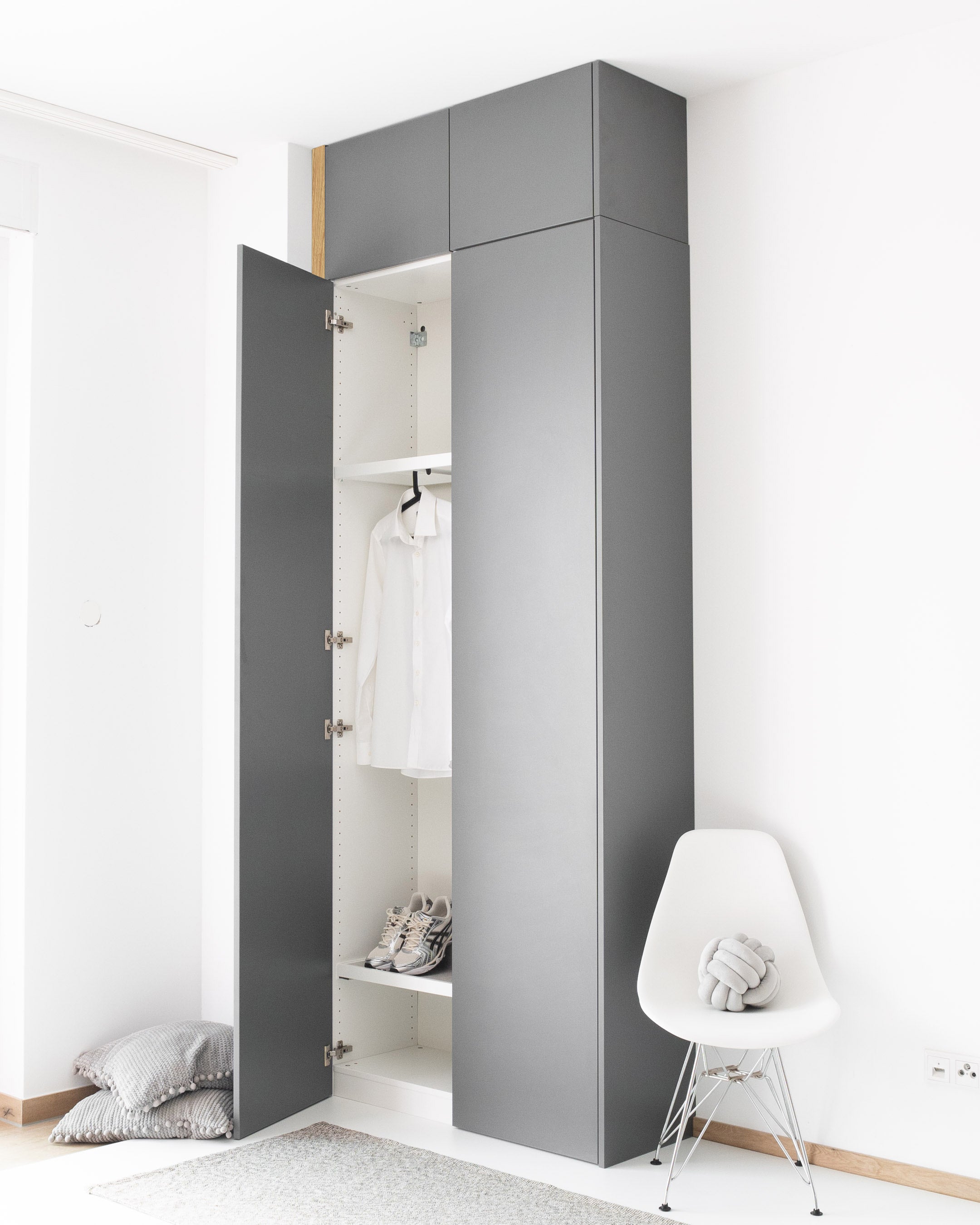 Eine graue Wandblende aus Holzdekor schließt den Spalt zwischen Schrank und Wand.