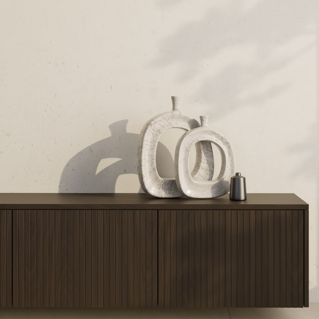 Ein dunkles Sideboard mit gerillten Holzfronten, dekoriert mit zwei abstrakten, hellen Vasen.