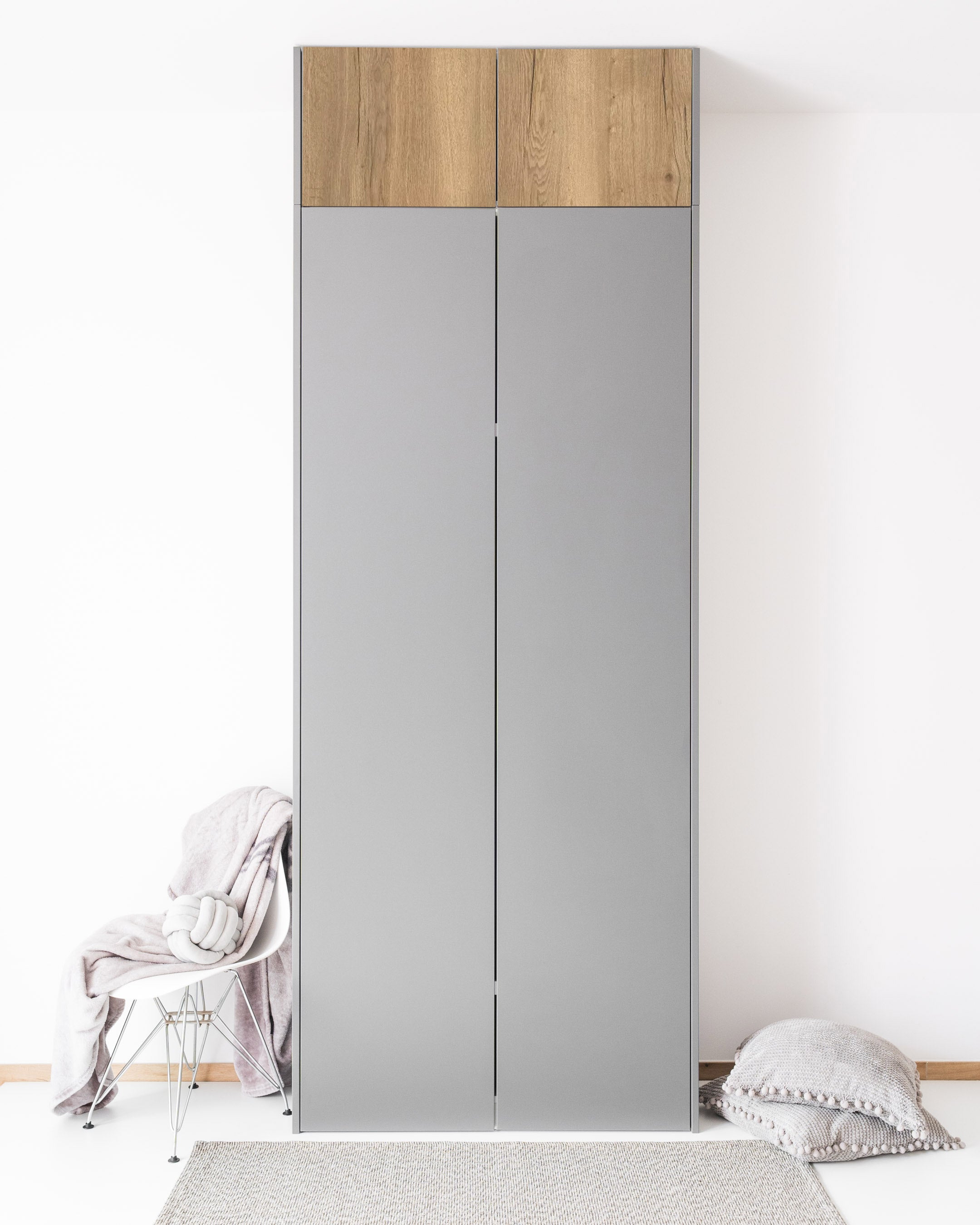 PAX Aufsatzschrank mit Türen in Holzoptik und grauen Fronten in einem hellen Raum.