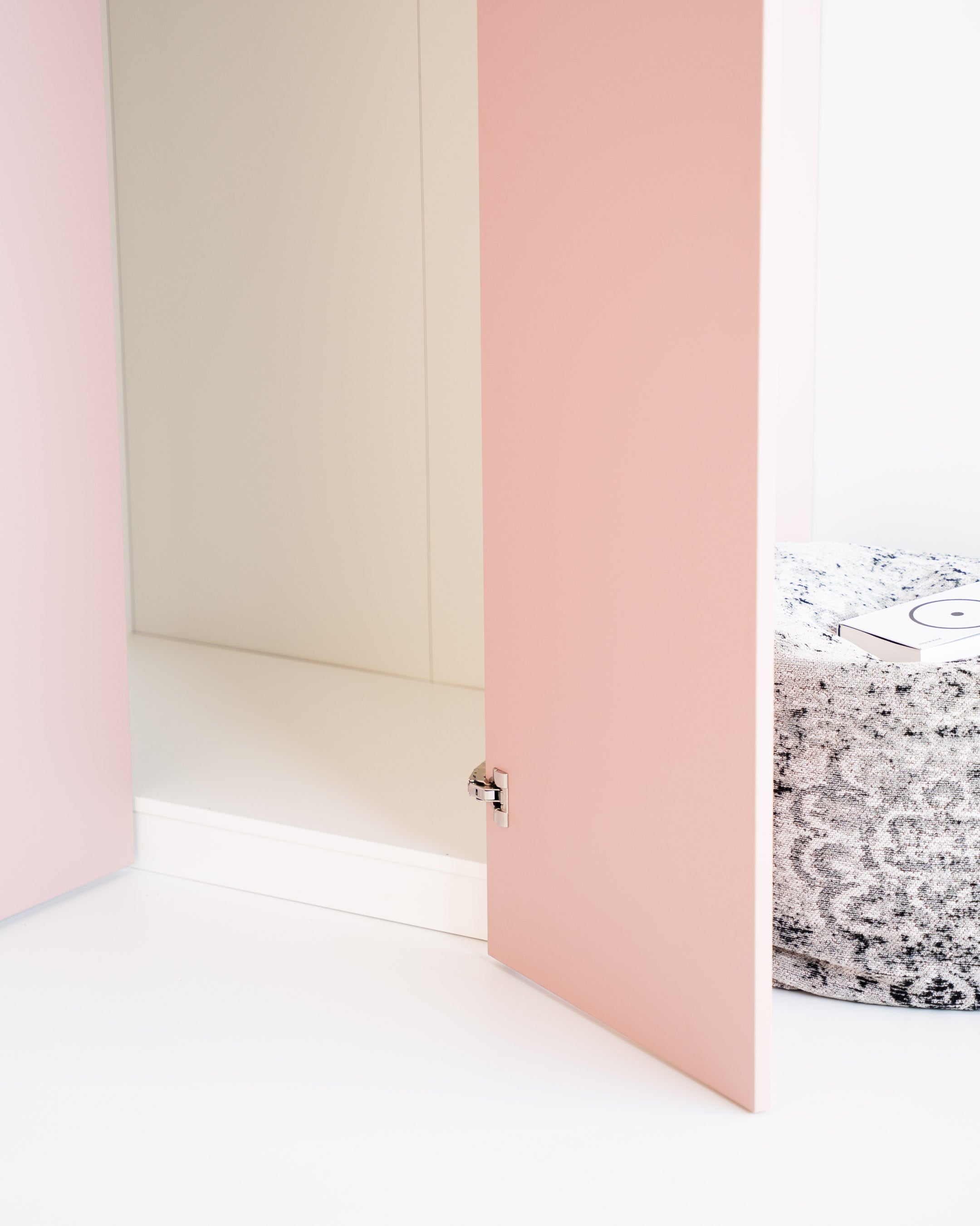 Ein 155 Grad Blum Eckscharnier montiert an einer rosafarbenen Schranktür.