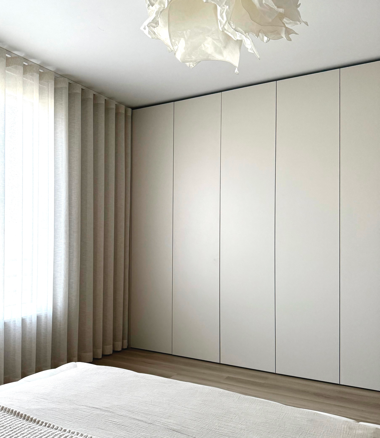 A minimalist bedroom featuring a floor-to-ceiling angoragrau wardrobe and matching curtains.