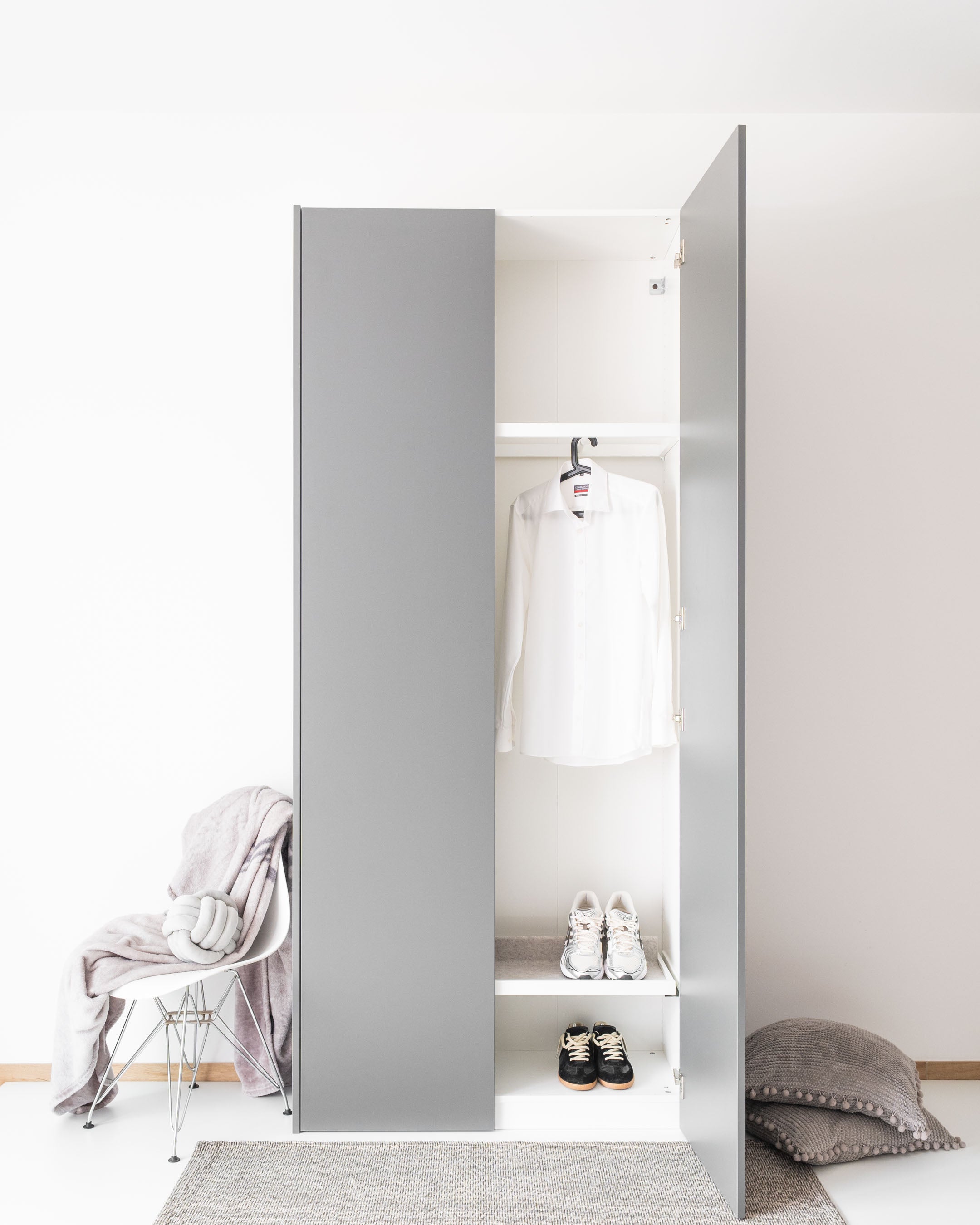 Eine graue, bodentiefe PAX Tür Aurora Pure an einem Kleiderschrank in einem hellen Raum.